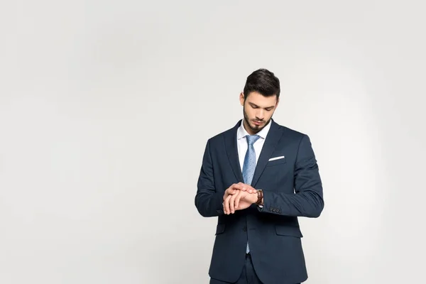 Moda joven hombre de negocios comprobar reloj de pulsera aislado en gris - foto de stock