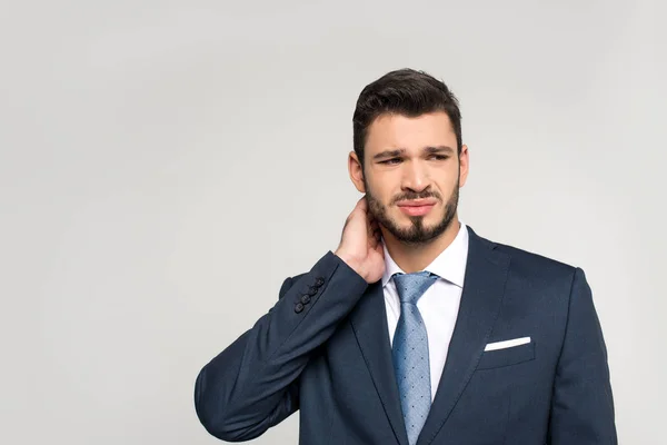 Young businessman suffering from pain in neck and looking away isolated on grey — Stock Photo