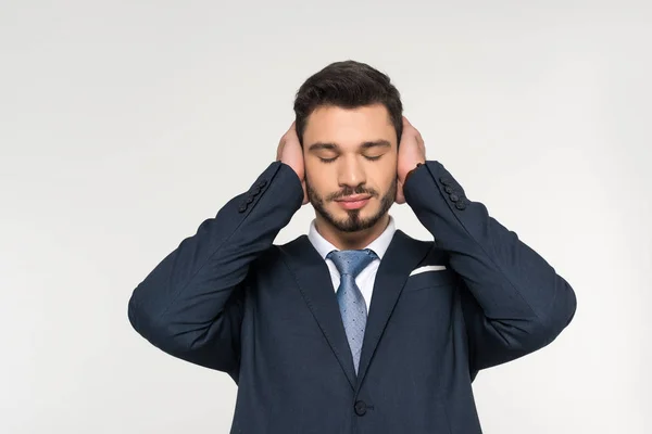 Giovane uomo d'affari rilassato con gli occhi chiusi che chiude le orecchie con le mani isolate sul grigio — Foto stock