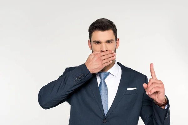 Молодий бізнесмен закриває рот долонею і вказує пальцем ізольовано на сірий — стокове фото