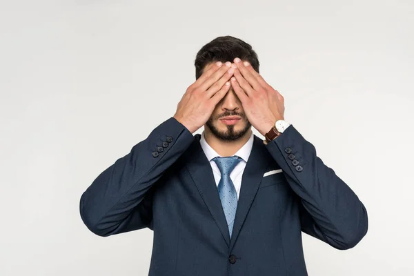 Young businessman closing eyes with hands isolated on grey — Stock Photo