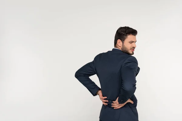 Vista posteriore del giovane imprenditore che soffre di mal di schiena isolato su grigio — Stock Photo