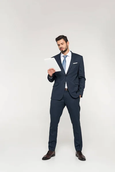 Full length view of confident young businessman using digital tablet isolated on grey — Stock Photo