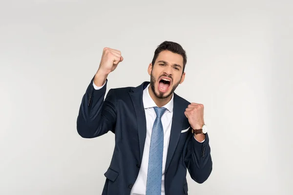 Excited young businessman shaking fists and screaming at camera isolated on grey — Stock Photo
