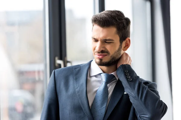 Young businessman suffering from pain in neck — Stock Photo