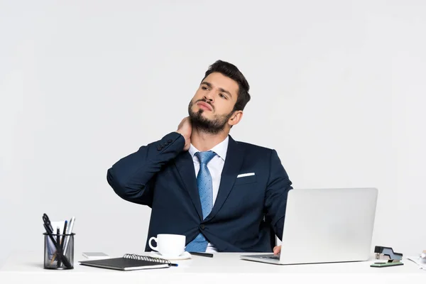 Young businessman suffering from pain in neck while using laptop at workplace — Stock Photo