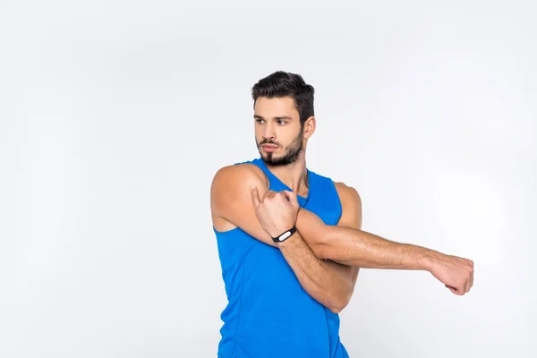 Handsome sporty man stretching hands and looking away isolated on white — Stock Photo