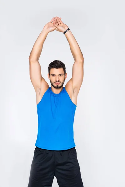 Handsome sporty man stretching hands and looking at camera isolated on white — Stock Photo