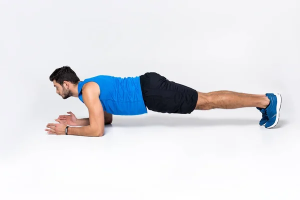 Sportlicher junger Mann beim Planken auf weißem Grund — Stockfoto