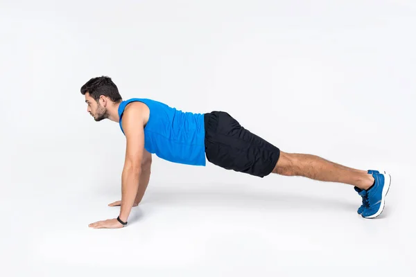 Vista lateral del joven haciendo flexiones en blanco - foto de stock