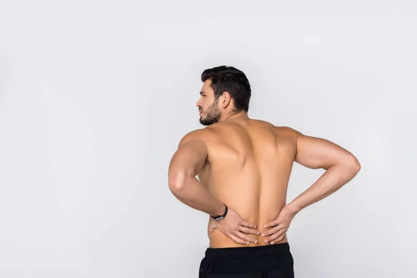 Вид ззаду молодого без сорочки чоловіка з болем у спині ізольовано на білому — стокове фото