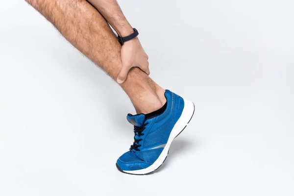 Cropped shot of runner holding leg while in hurts on white — Stock Photo