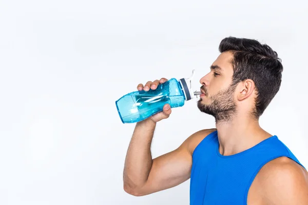 Vista laterale del giovane sportivo che beve acqua dalla bottiglia di fitness isolata sul bianco — Foto stock