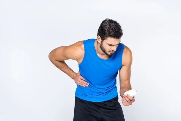 Giovane con mal di stomaco guardando vaso di pillole isolate su bianco — Foto stock