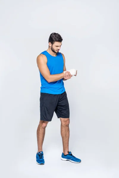 Sporty young man with pain in bandaged hand isolated on white — Stock Photo