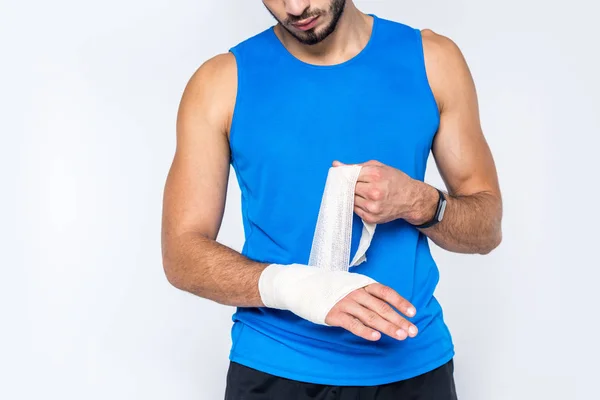 Abgeschnittene Aufnahme eines jungen Mannes, der sein Handgelenk mit Verband abdeckt, isoliert auf weiß — Stockfoto