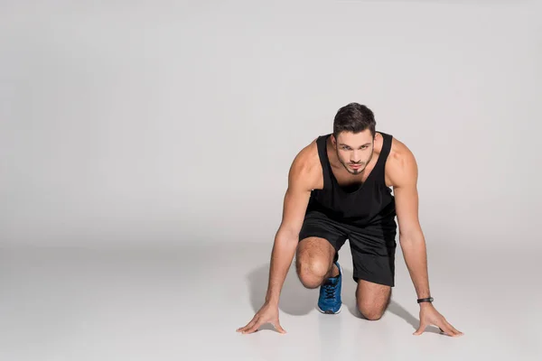 Handsome young runner in start position on white — Stock Photo