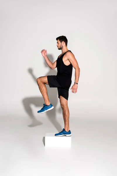 Vue latérale de l'homme sportif faisant de l'aérobic pas à pas sur bloc — Photo de stock