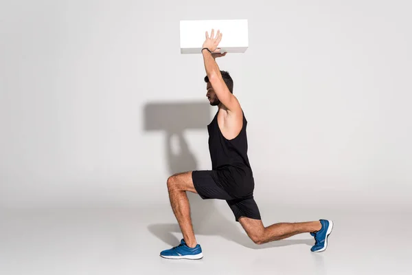 Vue latérale de jeune homme faisant squats avec bloc — Photo de stock