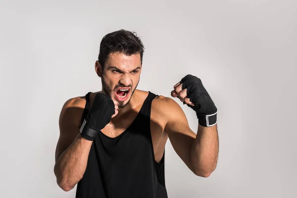 Agresivo luchador gritando con las manos vendadas aisladas en gris - foto de stock