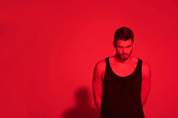 Angry young man under contrast red light — Stock Photo