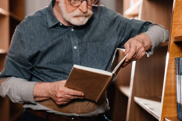 Cropped image of grey hair librarian reading book — Stock Photo