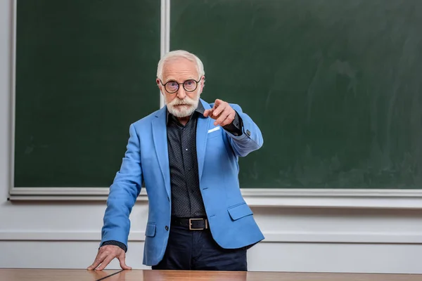 Senior lecturer pointing on something in lecture room — Stock Photo