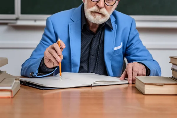 Image recadrée de conférencier principal réfléchi assis à table avec crayon et cahier — Photo de stock