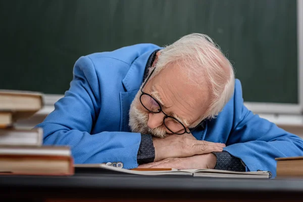 Profesor senior durmiendo en la mesa de trabajo - foto de stock