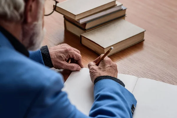 Imagen recortada de profesor senior escribiendo algo en el cuaderno - foto de stock