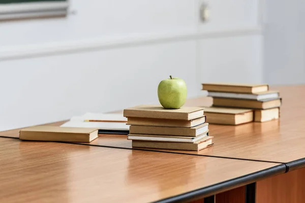 Ripe apple on stack of books on table in lecture room — Stock Photo