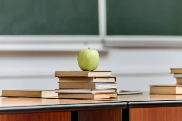Ripe apple on stack of books on table in lecture room — Stock Photo