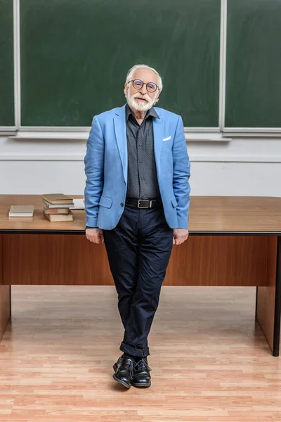 Grey hair professor standing in lecture room and looking at camera — Stock Photo