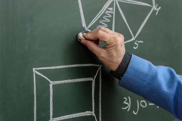 Cropped image of professor drawing with piece of chalk at blackboard — Stock Photo