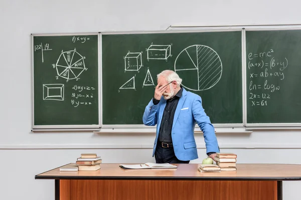 Tired grey hair professor touching eyes at blackboard — Stock Photo