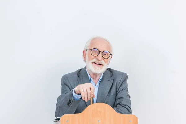 Glücklicher Senior Dozent steht an hölzerner Tribüne isoliert auf weiß — Stockfoto