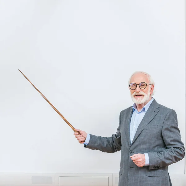 Улыбающийся старший преподаватель, указывающий на что-то на белом экране с деревянной указкой — стоковое фото