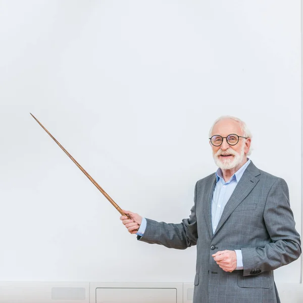 Conférencier principal souriant pointant sur quelque chose à l'écran blanc avec pointeur en bois — Photo de stock