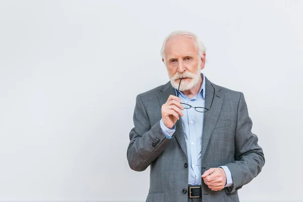 Profesor sénior mordiendo gafas aisladas en blanco - foto de stock