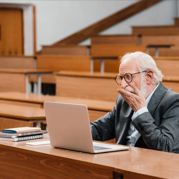 Professeur de cheveux gris bâillant dans la salle de conférence vide — Photo de stock