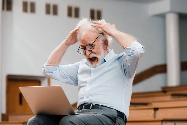 Palestrante sênior em sala de aula vazia gritando e olhando para laptop — Stock Photo