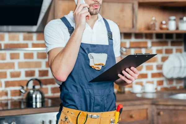 Schnappschuss von Vorarbeiter, der Klemmbrett hält und per Smartphone spricht — Stockfoto