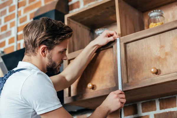 Schöner junger Polier misst Küchenmöbel mit Klebeband — Stockfoto