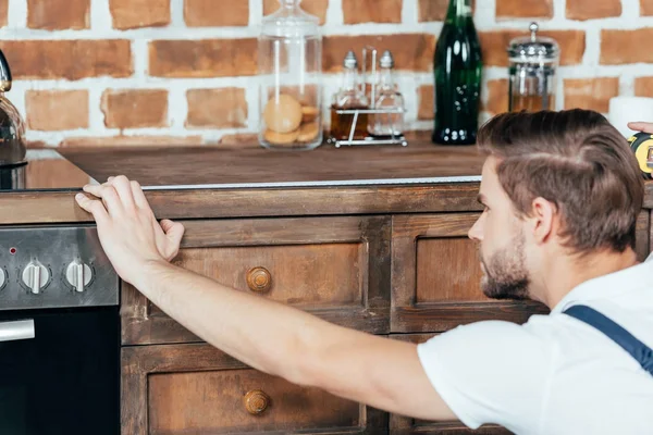 Selective focus of young foreman measuring kitchen furniture with tape — Stock Photo