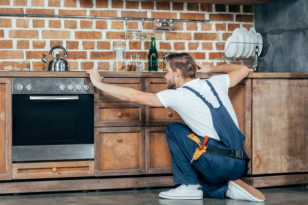 Back view of young foreman measuring kitchen furniture with tape — Stock Photo