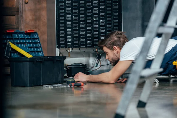 Selective focus of young foreman fixing refrigerator — Stock Photo