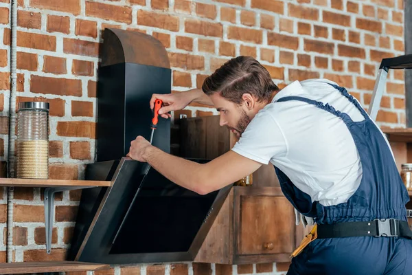 Профессиональный молодой мастер ремонт кухонного капюшона с отверткой — стоковое фото