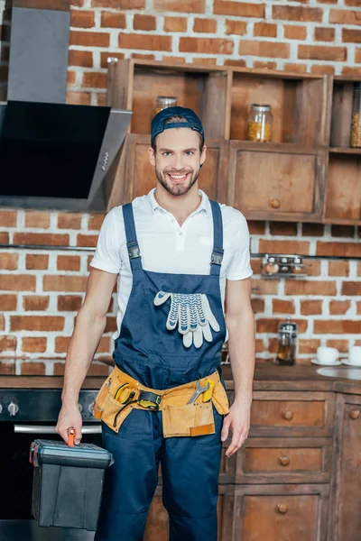 Professioneller Heimwerker mit Werkzeugkiste und Werkzeuggürtel lächelt in die Kamera — Stockfoto