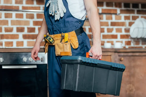 Cropped shot of home master with tool belt holding toolbox — Stock Photo