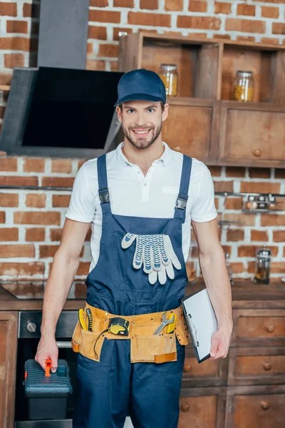 Professioneller Heimwerker mit Werkzeugkiste und Klemmbrett lächelt in die Kamera — Stockfoto